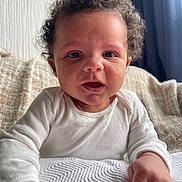 Ellis joined the competition — help win amazing prizes! baby, blanket, child, closeup, couch, curly_hair, cute, expression, face, hands, home, indoor, infant, person, portrait, relaxed, smile, soft_light, white_onesie, young