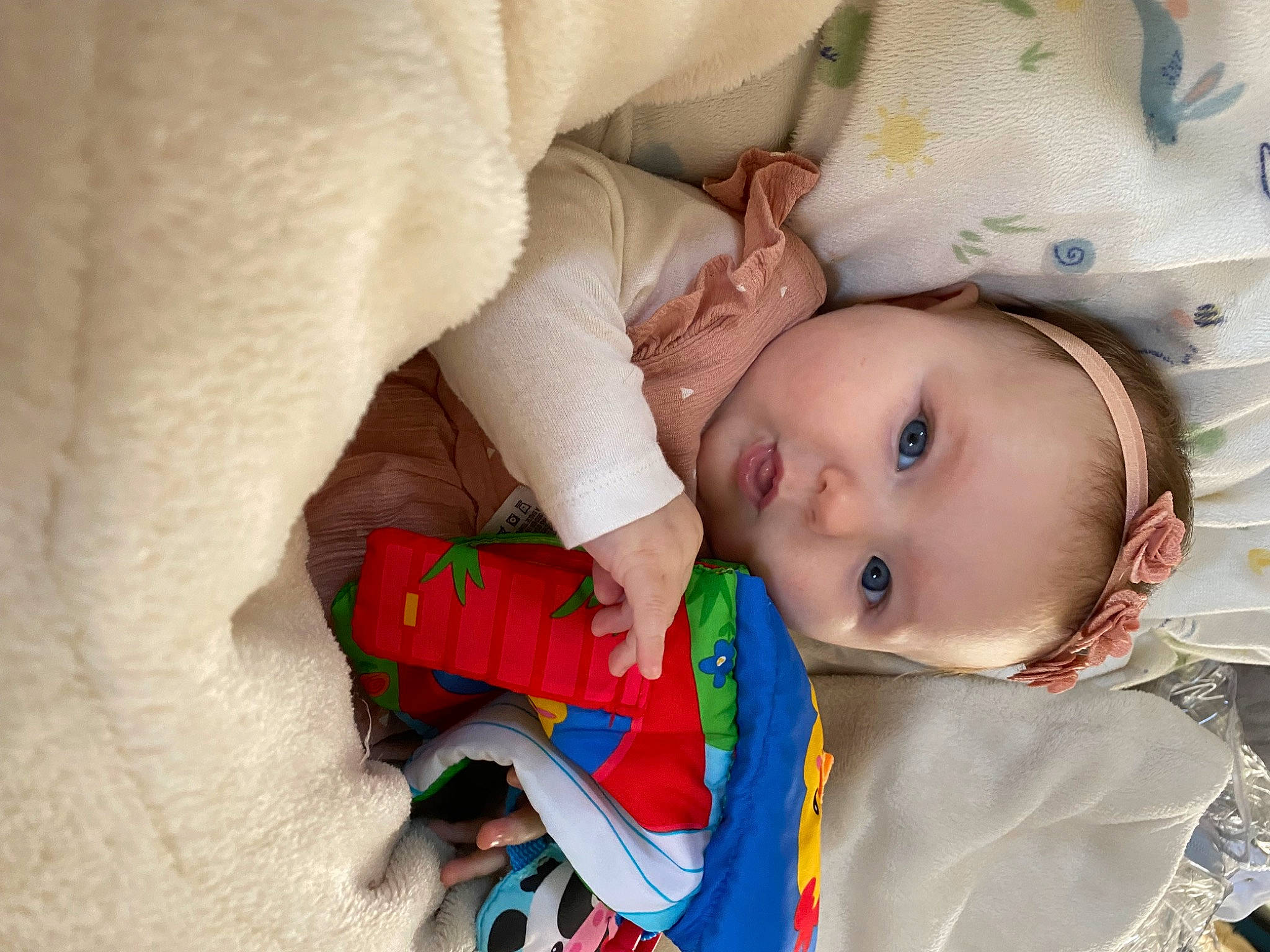 Sophie participe au concours pour gagner de l'argent avec cette photo : baby, baby_products, baby_toddler_clothing, cheek, child, comfort, eye, happy, human_body, iris, linens, mouth, nose, pattern, person, sitting, skin, sleeve, textile, toddler