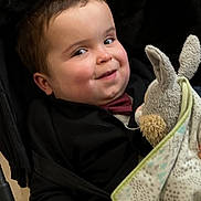 Link participe au concours pour gagner de l'argent avec cette photo : baby, black_jacket, blanket, bow_tie, bunny, candid, child, cozy, cute, expression, fabric, face, hand, indoors, plush_toy, portrait, seated, smiling, soft_toy, toddler