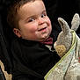baby, black_jacket, blanket, bow_tie, bunny, candid, child, cozy, cute, expression, fabric, face, hand, indoors, plush_toy, portrait, seated, smiling, soft_toy, toddler