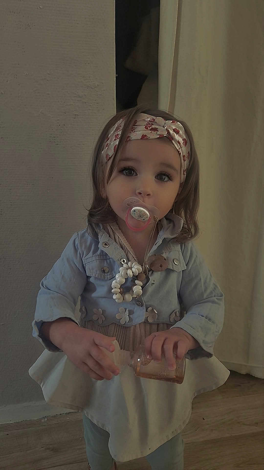 Fybie a rejoint le concours — aidez-le/la à gagner de superbes lots ! toddler, child, pacifier, headband, jacket, dress, indoor, floor, wooden_floor, curious, baby, clothing, person, small_bottle, long_hair, standing, cute, girl, young_child, portrait