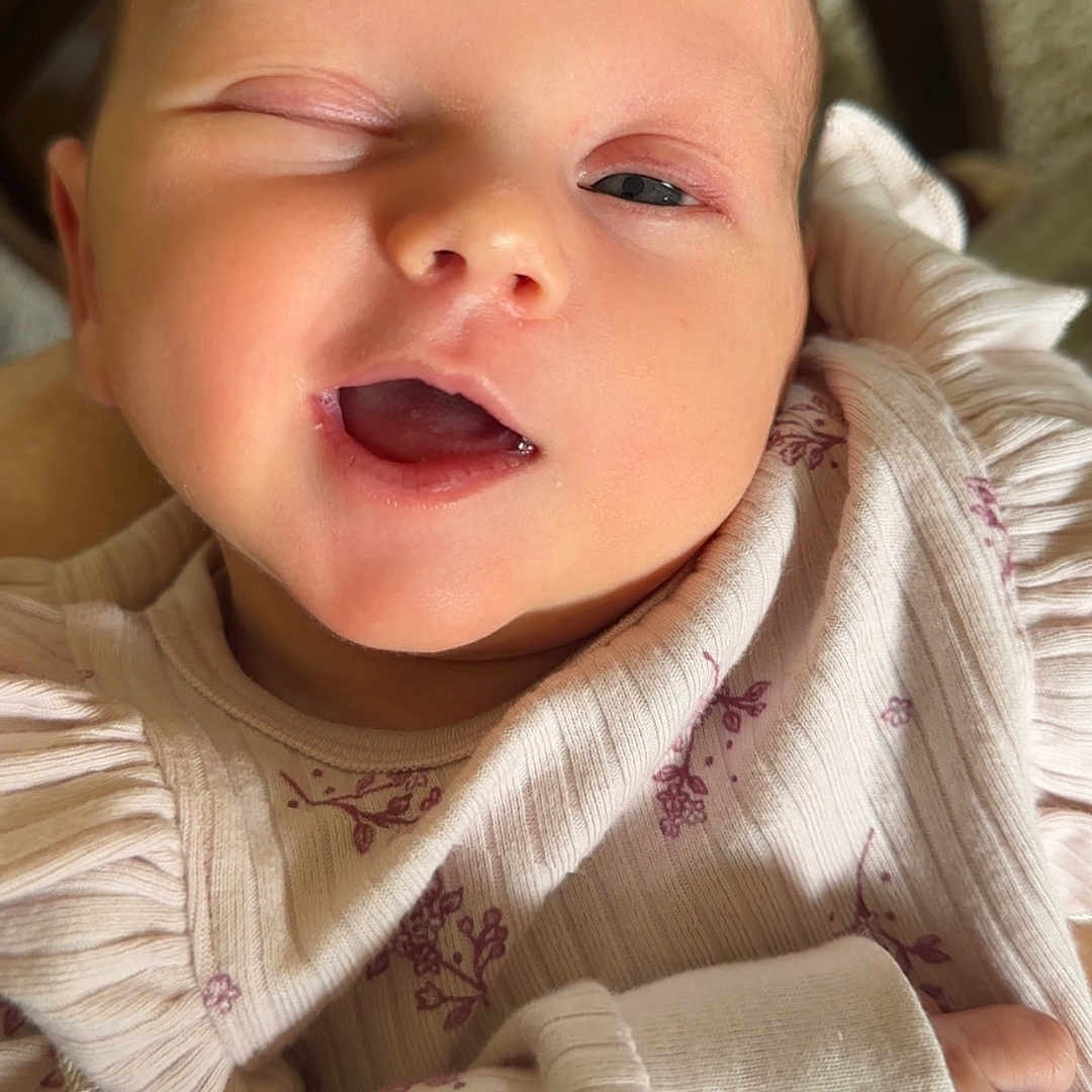 Riverleigh is registered to the contest to win money with this photo: baby, babylaughing, bodypart, clothing, face, finger, hand, happy, head, knitwear, laughing, longsleeve, mouth, newborn, person, photography, portrait, sleeping, smile, sweater