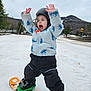 child, snowboard, helmet, winter_clothing, snow, mountain, outdoor, expression, arms_raised, jacket, pants, boots, sky, trees, snowboard_bindings, excited, sport, fun, active, cold_weather