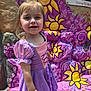 child, girl, princess_dress, purple_dress, smiling, outdoor, flower_mural, colorful_wall, leaf, sunlight, happy, portrait, costume, face, short_hair, daylight, stone_wall, playful, young_child, artistic_background
