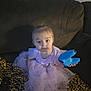 Freya is registered to the contest to win money with this photo: toddler, child, dress, tutu, couch, blanket, remote_control, toy, blue, purple, indoor, person, face, sitting, curious, home, furniture, arcade_machine, quarters, knitted_blanket