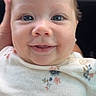 baby, infant, smiling, face, blue_eyes, white_clothing, floral_pattern, closeup, portrait, cute, happy, child, skin, newborn, person, young_child, head, gaze, innocence, soft_lighting