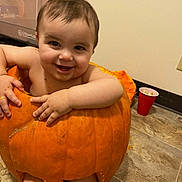 Vaeh joined the competition — help win amazing prizes! baby, pumpkin, smiling, messy, floor, orange, child, indoor, cute, halloween, fun, food, playful, person, skin, happy, hands, legs, face, mouth