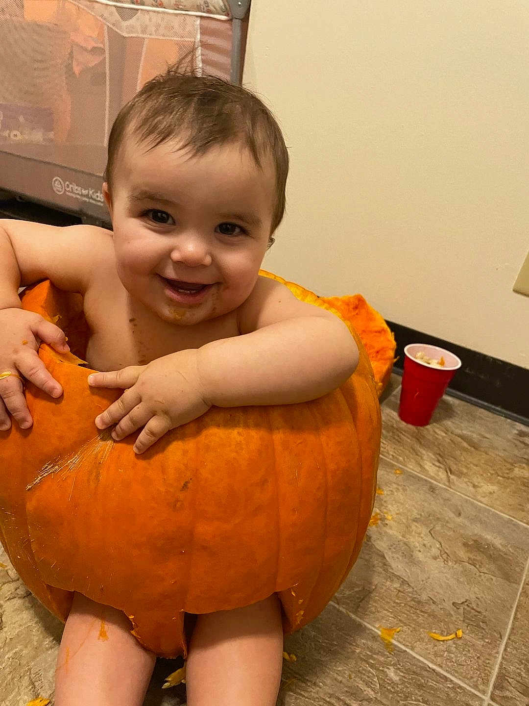 Vaeh joined the competition — help win amazing prizes! baby, pumpkin, smiling, messy, floor, orange, child, indoor, cute, halloween, fun, food, playful, person, skin, happy, hands, legs, face, mouth