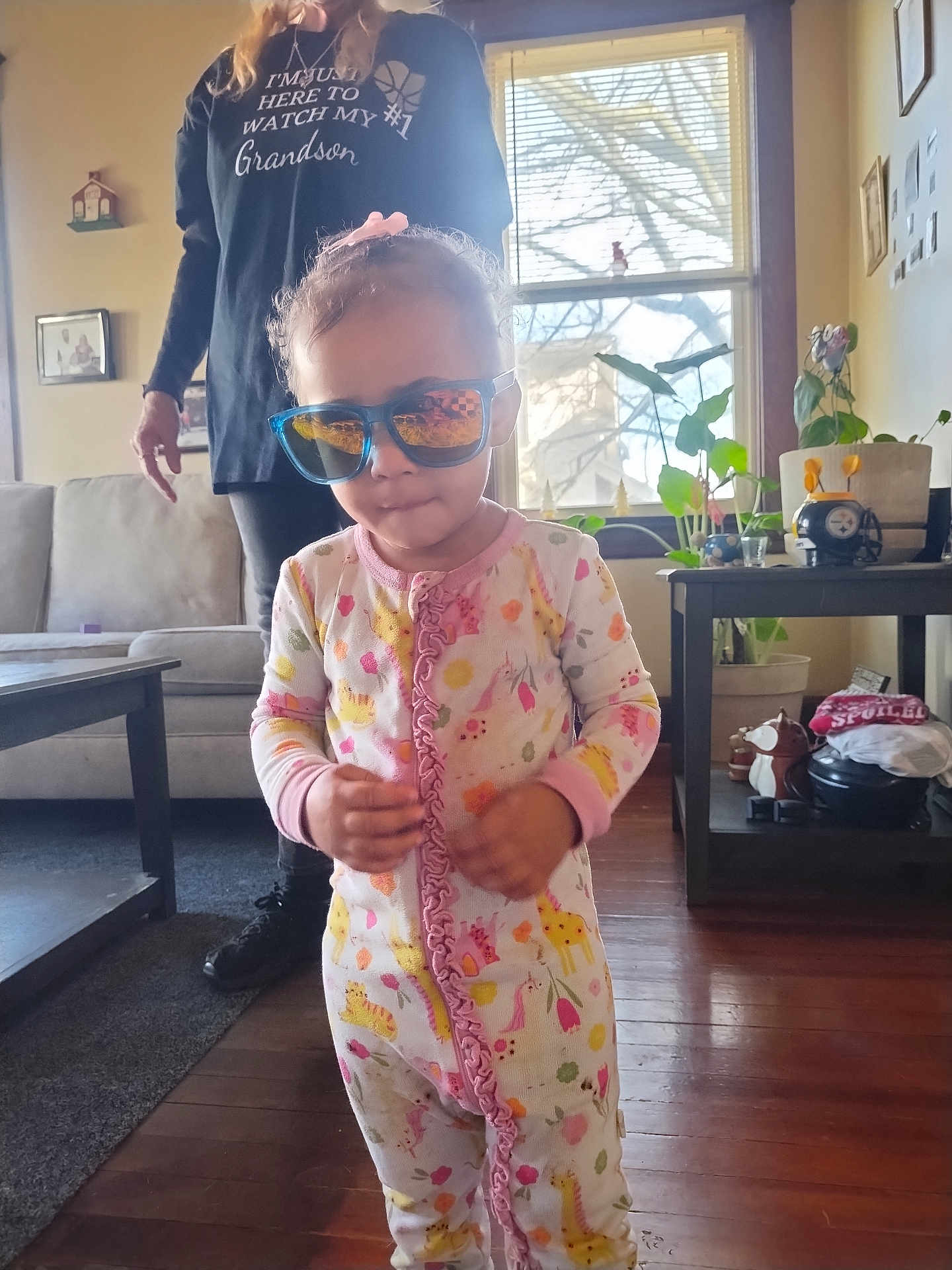 Rumanni joined the competition — help win amazing prizes! toddler, child, sunglasses, pajamas, woman, indoor, living_room, window, plants, furniture, floor, person, home, casual_clothing, wooden_floor, reflection, decor, family, cute, portrait