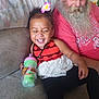 Rumanni is registered to the contest to win money with this photo: toddler, child, smiling, laughing, flower, hair_accessory, sippy_cup, beard, older_man, couch, red_shirt, cap, indoors, happy, person, clothing, seated, family, casual, home