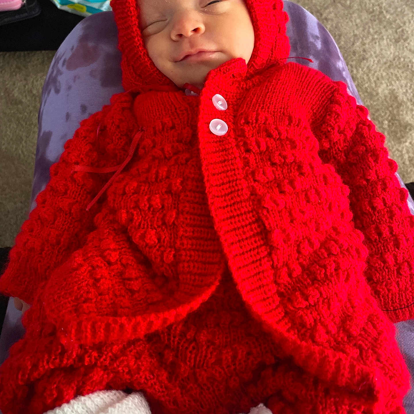 Marcy joined the competition — help win amazing prizes! baby, carpet, child, closeup, comfort, cozy, cushion, indoors, infant, knitted_clothing, peaceful, person, portrait, purple_cushion, red_hood, resting, sleeping, soft_lighting, warm_clothing, white_booties