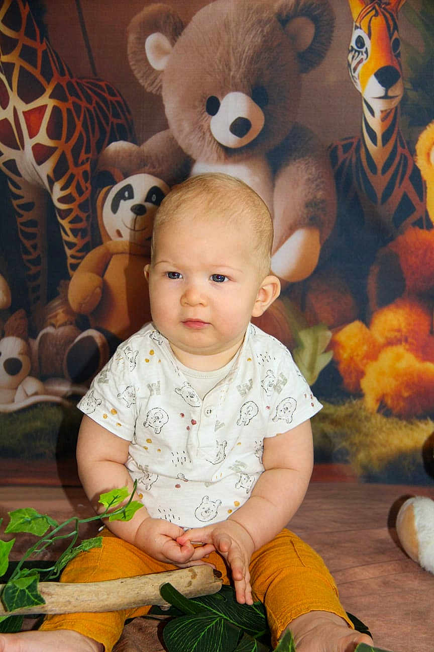 Aaron a rejoint le concours — aidez-le/la à gagner de superbes lots ! baby, child, toddler, indoor, stuffed_animals, plush_toys, giraffe, tiger, teddy_bear, panda, plant, greenery, orange_pants, white_shirt, floor, curious, serious, portrait, cute, explorer