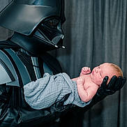 Owen joined the competition — help win amazing prizes! baby, darth_vader, costume, helmet, gloves, armor, blanket, newborn, infant, person, portrait, indoor, curtain, black_clothing, child, holding, side_view, face, caring, fantasy