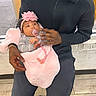 baby, infant, child, man, holding, indoor, window, pacifier, pink_blanket, headband, seated, floor_tiles, black_clothing, afro_hair, affection, parent_child, love, care, portrait, people