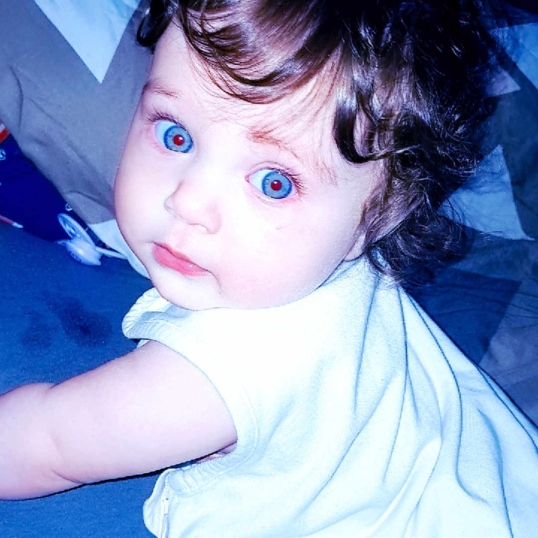 Inaya a rejoint le concours — aidez-le/la à gagner de superbes lots ! baby, bed, blanket, blue_eyes, child, curly_hair, cute, expression, face, flash, hand, indoor, infant, lying_down, person, portrait, red_eye, skin, sleeveless, white_clothing