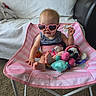 baby, child, infant, sunglasses, heart_shaped_sunglasses, pink, baby_chair, seated, toys, stuffed_animals, playroom, indoor, couch, blanket, carpet, striped_clothing, smiling, portrait, fashion, cute