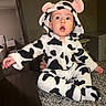 baby, child, onesie, cow_print, hood, ears, surprised, countertop, hand, indoor, clothing, person, infant, cute, expression, face, sitting, black_and_white, cozy, portrait
