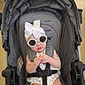 baby, stroller, sunglasses, headband, white_bow, child, infant, seatbelt, gray, cute, fashion, indoors, floor, baby_clothes, person, smiling, summer, accessory, seat, baby_fashion