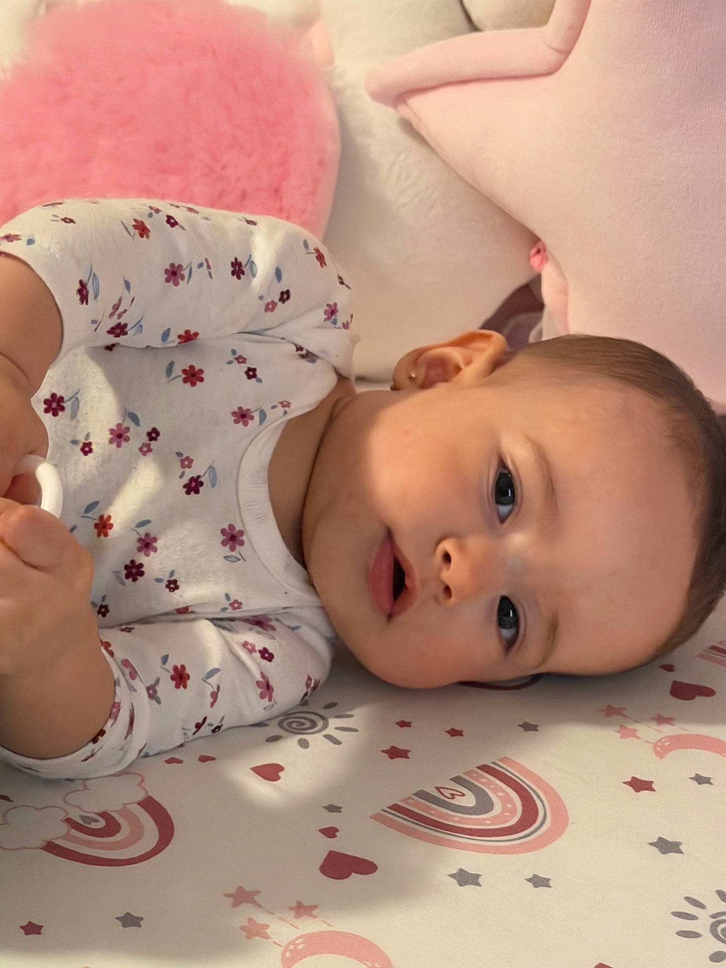 baby, child, curious, cute, expression, face, floral_pattern, fuzzy_pillow, hands, head, indoors, infant, lying_down, onesie, pink, playmat, plush_toy, soft_toys, star_shaped_pillow, young_child
