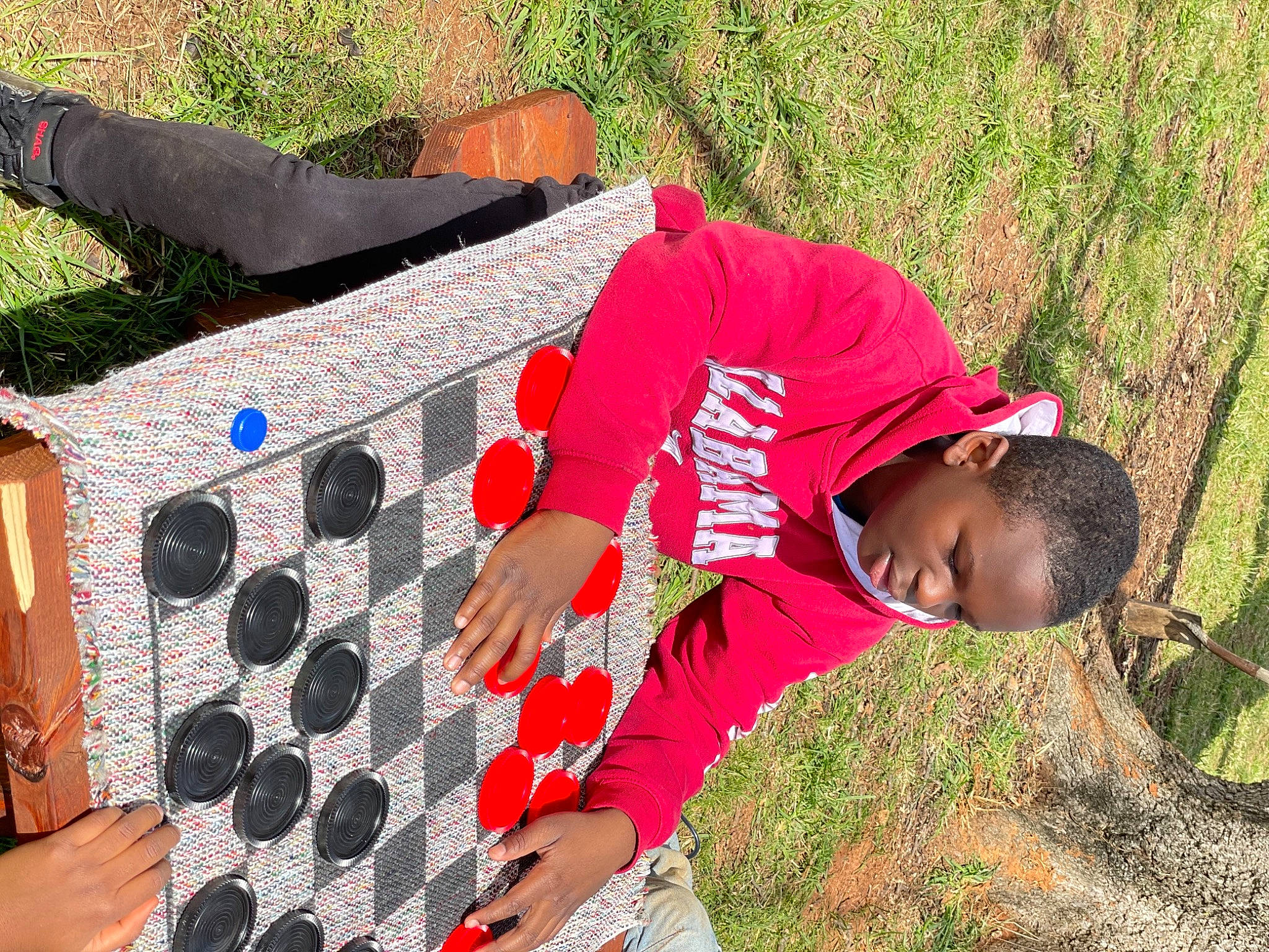 Tré is registered to the contest to win money with this photo: black, child, fun, grass, green, happy, hat, leisure, outdoor_furniture, pattern, people_in_nature, person, plant, play, recreation, shorts, sitting, soil, t_shirt, toddler