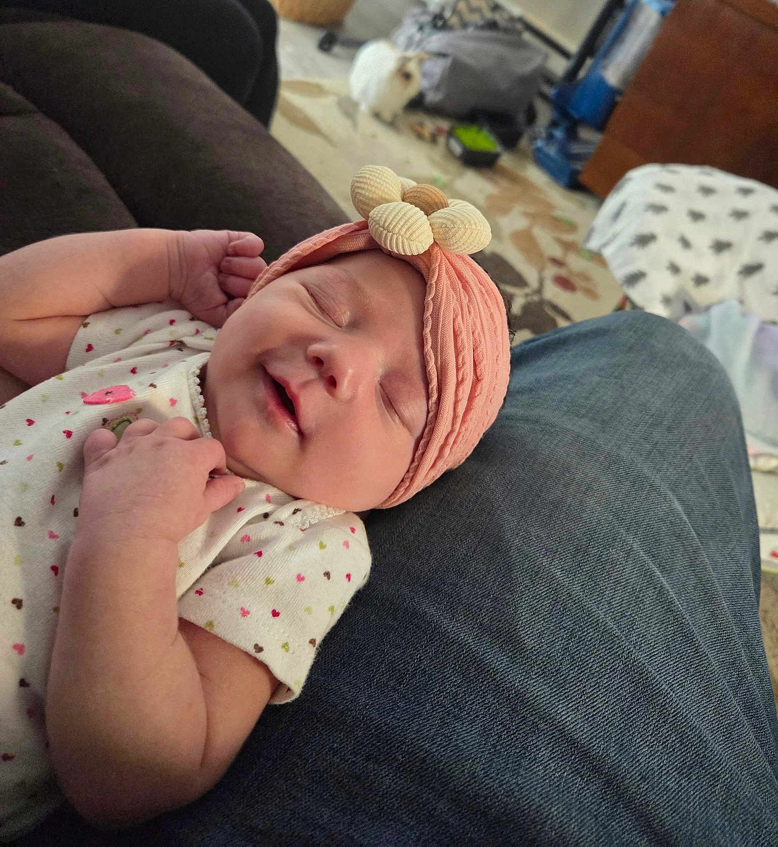 Ruby is registered to the contest to win money with this photo: baby, sleeping, headband, flower, pink, clothing, denim, lap, person, living_room, carpet, rabbit, pet, furniture, couch, blanket, cozy, indoor, cute, relaxing
