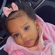 Cyamei is registered to the contest to win money with this photo: toddler, child, pink_jacket, bow, curly_hair, face, ears, eyes, car_interior, dashboard, clothing, cute, portrait, baby, earrings, seat, seatbelt, warm_clothing, indoors, person