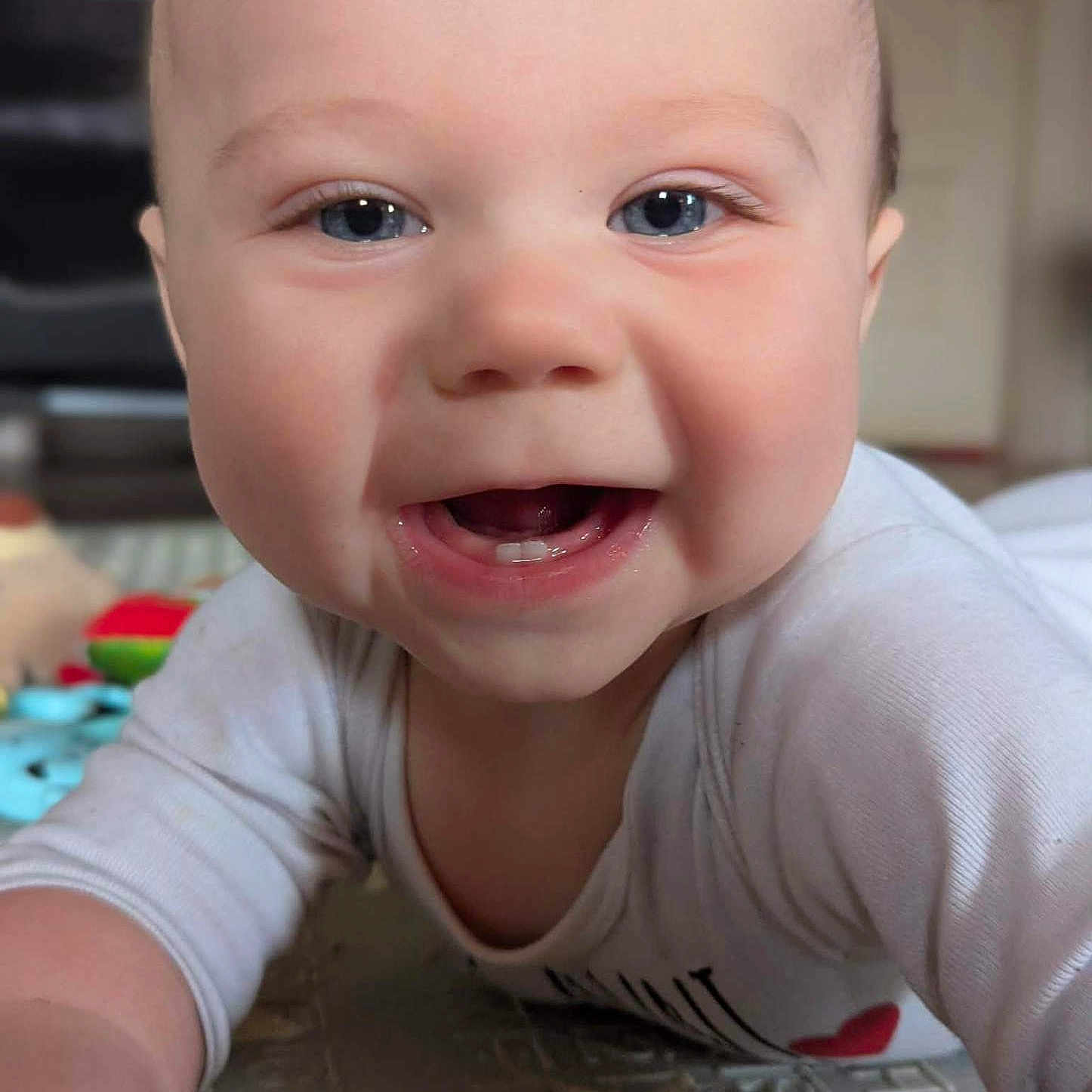 Noah joined the competition — help win amazing prizes! baby, infant, smiling, crawling, close_up, blue_eyes, teeth, white_clothing, indoor, floor_mat, cute, happy, child, portrait, skin, person, young, playful, cheerful, head