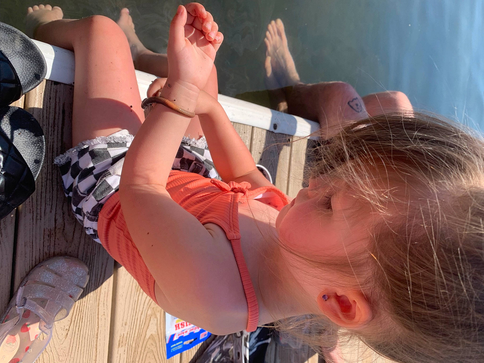 Penelope is registered to the contest to win money with this photo: body_of_water, elbow, eyewear, fun, gesture, happy, human_leg, knee, leg, leisure, mouth, people, people_in_nature, person, photograph, recreation, summer, sunglasses, thigh, toddler