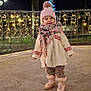toddler, child, winter_clothing, hat, scarf, boots, outdoor, night, lights, fairy_lights, pole, fence, curious, smile, cold_weather, park, concrete_floor, cute, fashion, cozy