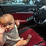 Wes joined the competition — help win amazing prizes! baby, child, car_interior, red_leather_seat, infant, window, steering_wheel, sunlight, clouds, blue_sky, car_door, car_window, seatbelt, hand, foot, clothing, dinosaur_print, parking_lot, flags, stop_sign
