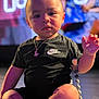 Wes is registered to the contest to win money with this photo: baby, child, infant, black_clothing, nike, pacifier, necklace, sitting, indoor, cute, portrait, face, young_child, person, closeup, expression, detailed, skin, hand, floor