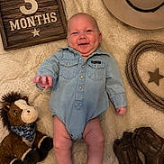 Henry joined the competition — help win amazing prizes! baby, infant, denim_onesie, cowboy_hat, cowboy_boots, rope, plush_horse, wooden_sign, soft_blanket, smiling, lying_down, cute, child, portrait, indoor, baby_clothes, toy, celebration, milestone, happy