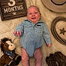 baby, infant, denim_onesie, cowboy_hat, cowboy_boots, rope, plush_horse, wooden_sign, soft_blanket, smiling, lying_down, cute, child, portrait, indoor, baby_clothes, toy, celebration, milestone, happy