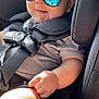 baby, child, car_seat, sunglasses, reflection, smile, sunlight, seatbelt, clothing, arm, hand, head, face, infant, transport, safety, casual, cute, portrait, indoor