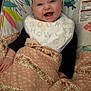 baby, smiling, happy, blanket, bib, floral_pattern, baby_chair, colorful, infant, cute, child, portrait, indoor, playful, animal_print, clothing, hand, face, person, joyful