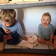 Louise participe au concours pour gagner de l'argent avec cette photo : child, baby, playpen, pajamas, blanket, toy, smile, blue_eyes, curly_hair, indoor, floor, wooden_floor, cute, happy, sitting, toddler, infant, star_pattern, cozy, family