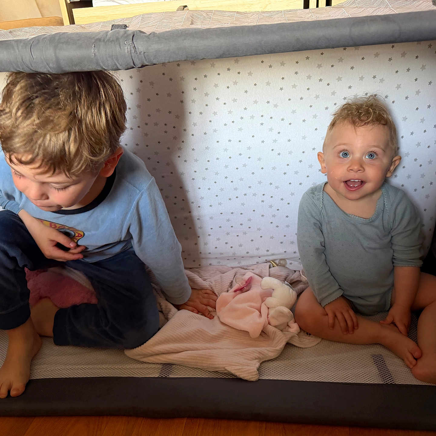 Louise participe au concours pour gagner de l'argent avec cette photo : child, baby, playpen, pajamas, blanket, toy, smile, blue_eyes, curly_hair, indoor, floor, wooden_floor, cute, happy, sitting, toddler, infant, star_pattern, cozy, family