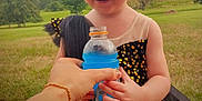 Rosalie joined the competition — help win amazing prizes! black_dress, blue_drink, bottle, child, cute, daylight, dress, fun, grass, hand, happy, joy, laughing, nature, outdoor, person, smiling, sparkly, toddler, trees
