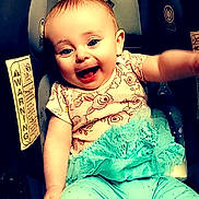 Rosalie joined the competition — help win amazing prizes! baby, child, car_seat, smiling, happy, clothing, floral, tutu, leggings, infant, cute, person, seat, sitting, young_child, indoors, joyful, face, head, arm