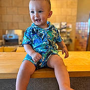 Zaid joined the competition — help win amazing prizes! baby, background_blur, barefoot, blue_clothing, casual, child, colorful, cute, face, happy, indoor, legs, playful, portrait, shorts, sitting, smiling, toddler, wooden_counter, young_child