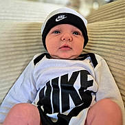 Adam a rejoint le concours — aidez-le/la à gagner de superbes lots ! baby, infant, nike, hat, clothing, couch, indoor, person, portrait, cute, child, young, sitting, face, headwear, apparel, comfortable, expression, closeup, relaxing