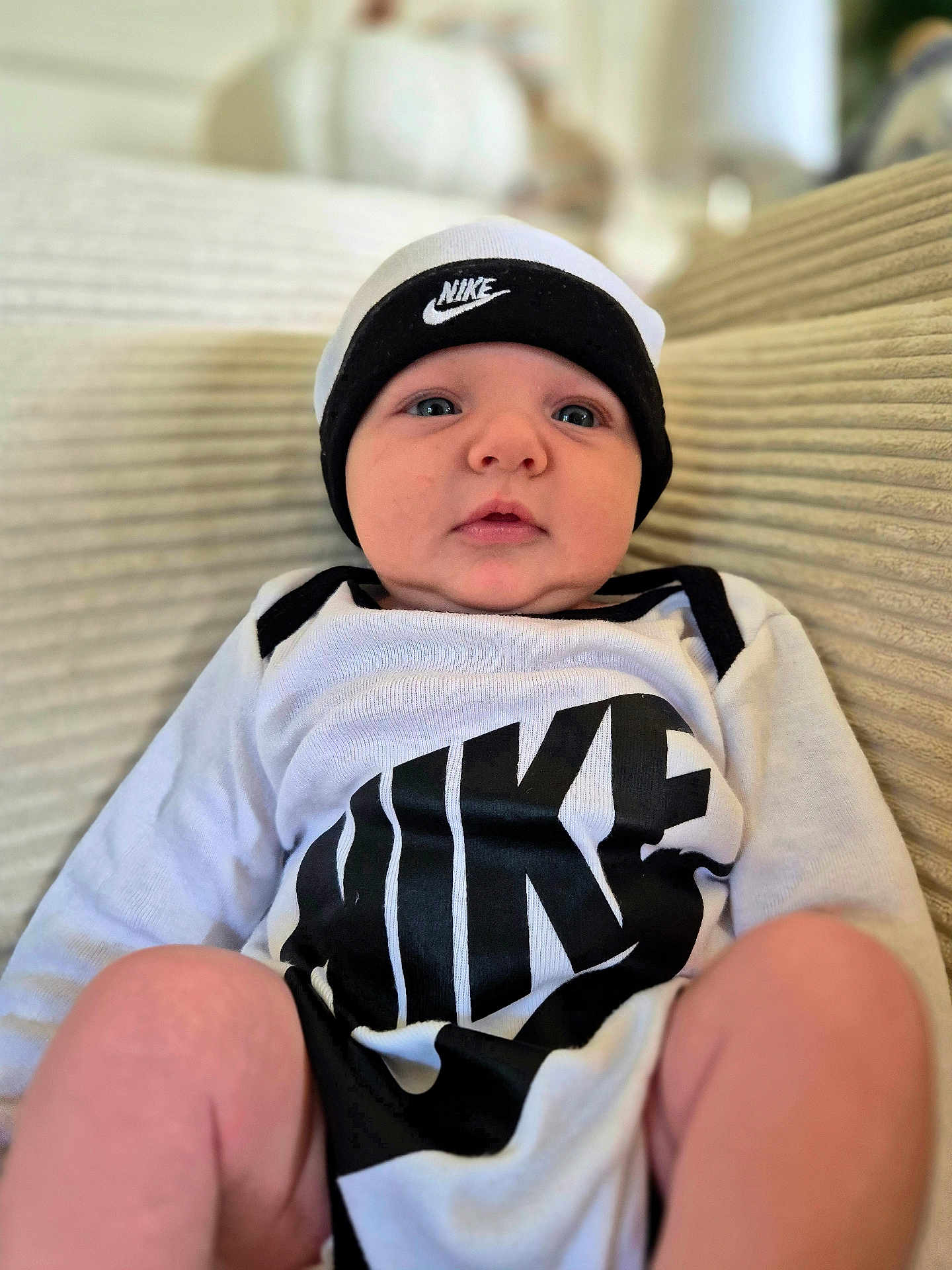 Adam a rejoint le concours — aidez-le/la à gagner de superbes lots ! baby, infant, nike, hat, clothing, couch, indoor, person, portrait, cute, child, young, sitting, face, headwear, apparel, comfortable, expression, closeup, relaxing