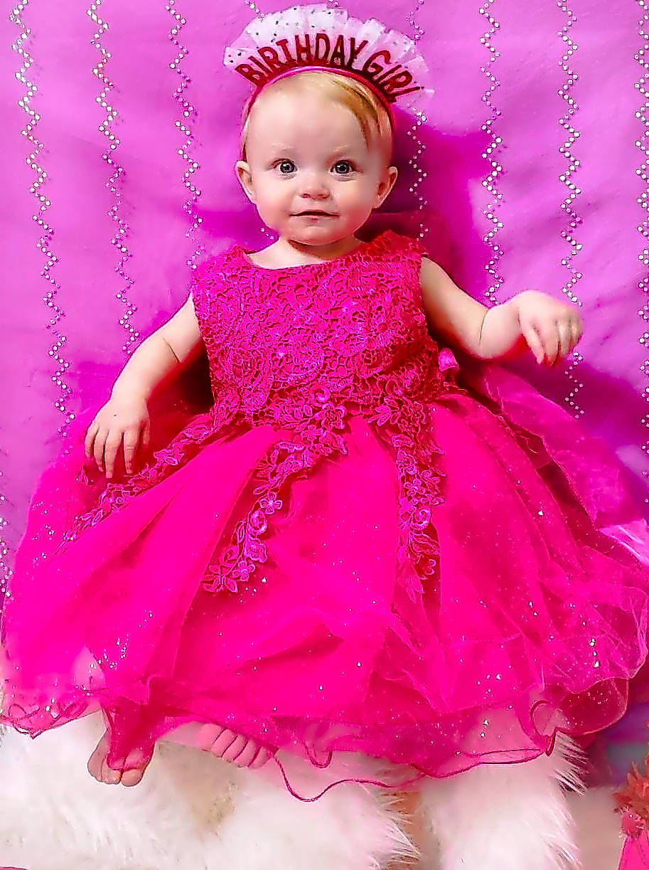 Kingstyn is registered to the contest to win money with this photo: baby_toddler_clothing, cheek, child, child_model, clothing, day_dress, dress, embellishment, hair_accessory, headgear, headpiece, lavender, magenta, pattern, person, pink, purple, sitting, skin, toddler