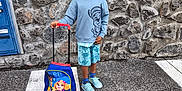 Luka Nathanaël participe au concours pour gagner de l'argent avec cette photo : backpack, boy, cartoon, casual_clothing, child, glasses, outdoor, pavement, paw_patrol, person, road_marking, serious, shorts, sneakers, socks, standing, stone_wall, sweatshirt, toy, travel