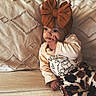 Bibianna joined the competition — help win amazing prizes! baby, child, headband, bow, couch, pillow, clothing, pattern, animal_print, cow_print, hand, face, portrait, cute, indoors, sitting, furniture, young_child, expression, cozy