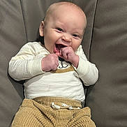Jakobe is registered to the contest to win money with this photo: baby, casual, child, clothing, corduroy_pants, cozy, cream_top, cute, expression, face, fist, happy, indoor, infant, joyful, laughing, portrait, seated, smiling, young_child