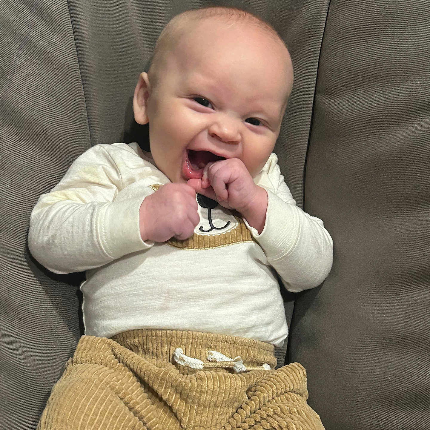 Jakobe is registered to the contest to win money with this photo: baby, casual, child, clothing, corduroy_pants, cozy, cream_top, cute, expression, face, fist, happy, indoor, infant, joyful, laughing, portrait, seated, smiling, young_child
