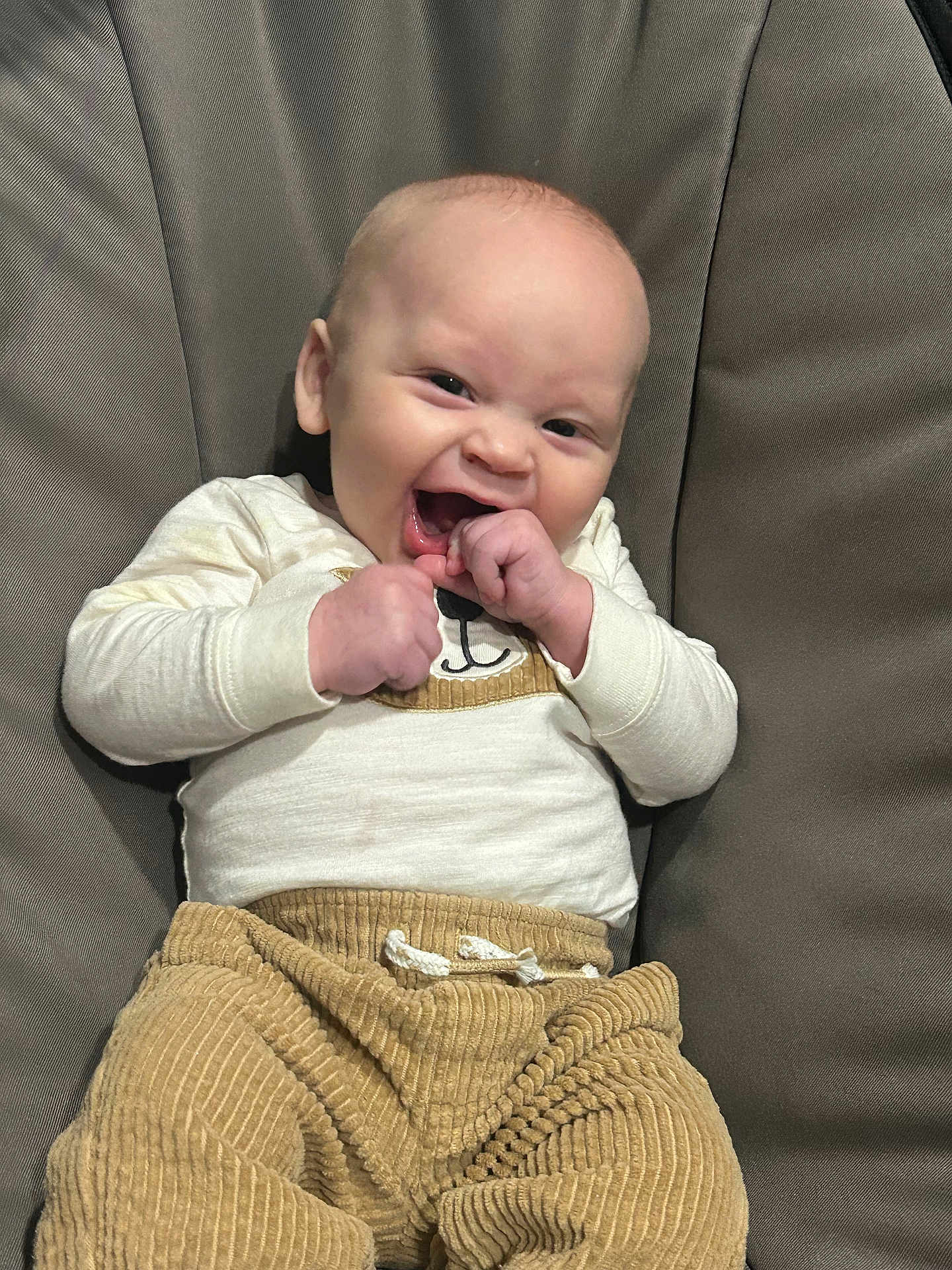 Jakobe is registered to the contest to win money with this photo: baby, casual, child, clothing, corduroy_pants, cozy, cream_top, cute, expression, face, fist, happy, indoor, infant, joyful, laughing, portrait, seated, smiling, young_child