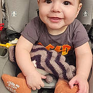 Logan is registered to the contest to win money with this photo: baby, infant, smile, car_seat, blanket, socks, hands, eyes, face, clothing, cute, portrait, buckle, cheeks, hair, soft_toy, fabric, headrest, harness, sitting