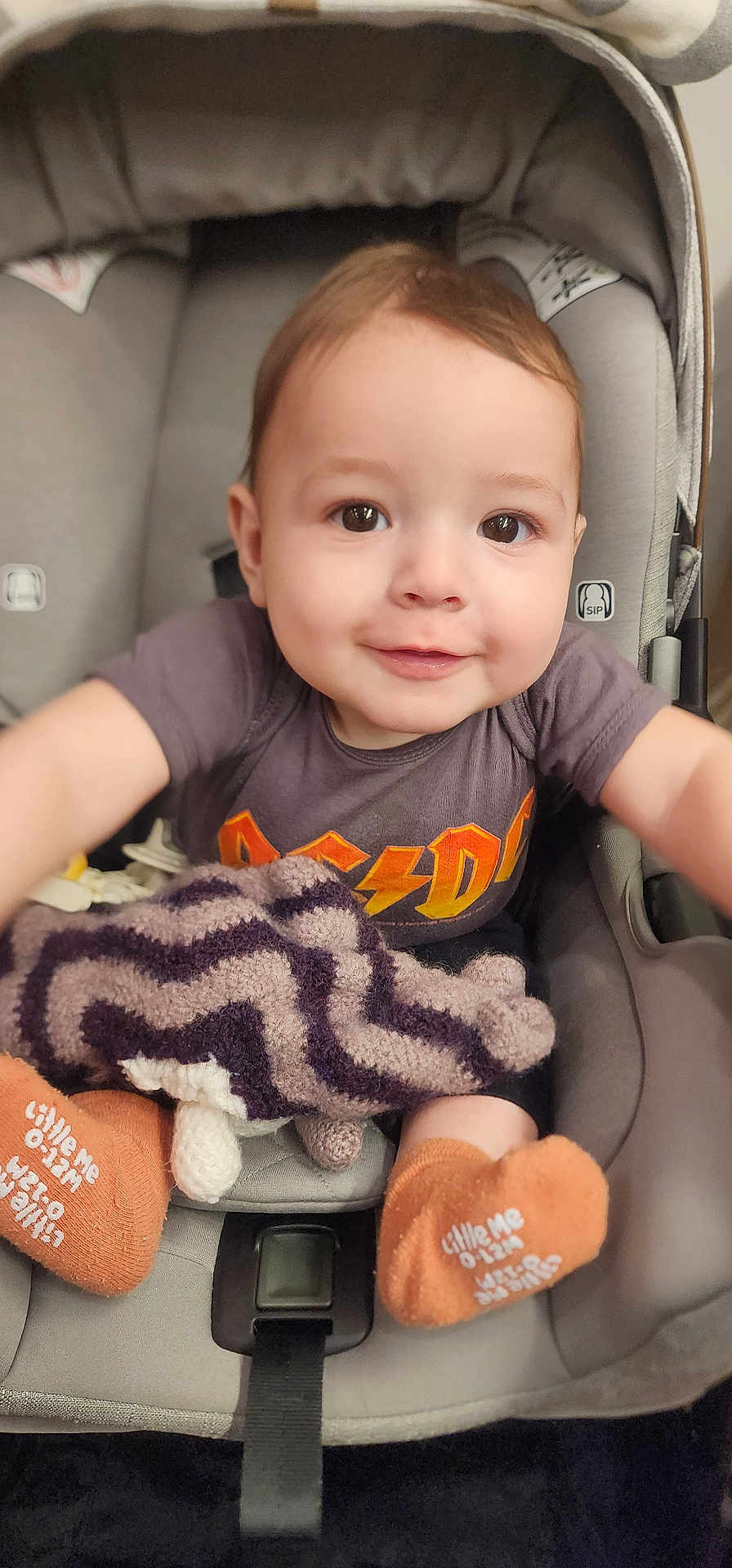 Logan joined the competition — help win amazing prizes! baby, infant, child, car_seat, smiling, portrait, blanket, socks, cute, brown_eyes, tshirt, seatbelt, canopy, hands, toy, plush_blanket, closeup, indoors, happy, cheeks